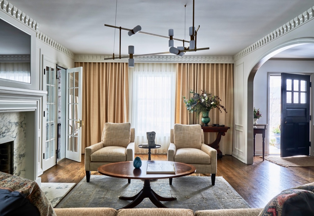 Living room with brass chandelier, drapery, marble fireplace, luxury renovation and interior design by Martire Custom Homes