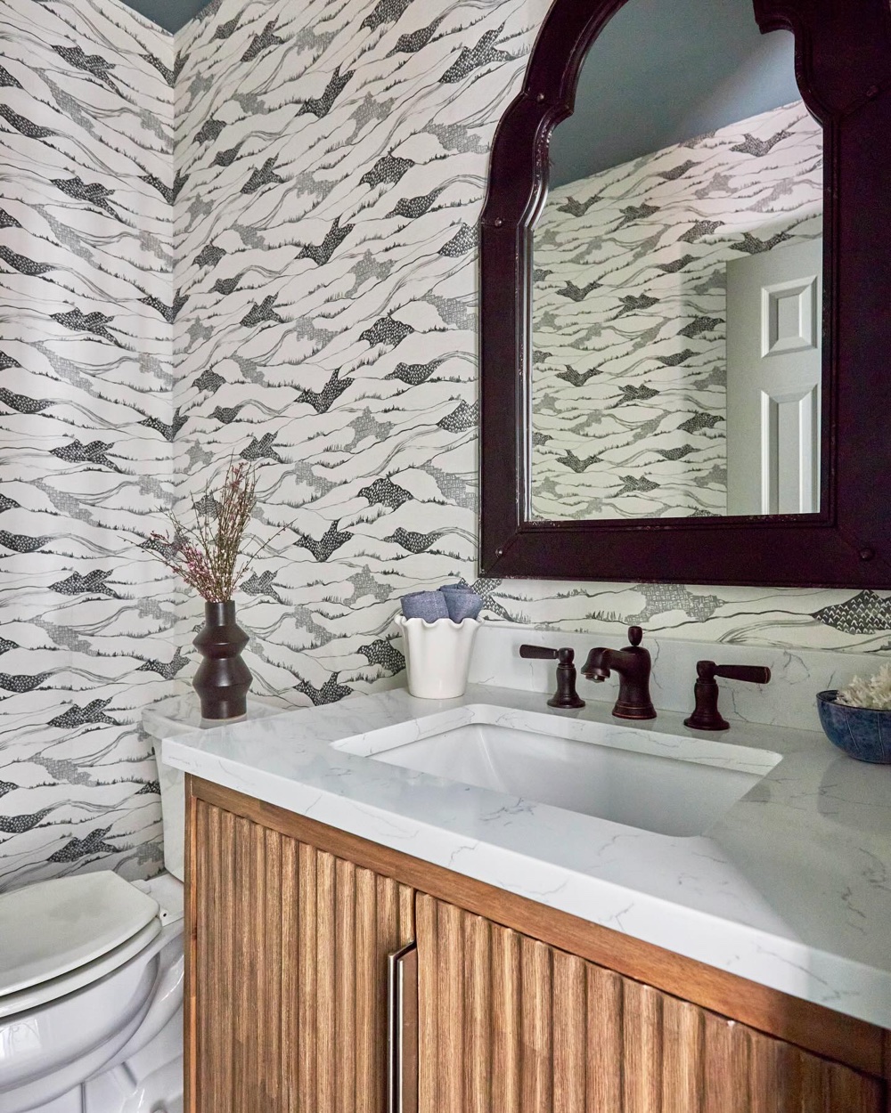 Powder room with patterned wallpaper and fluted vanity, luxury renovation and interior design by Martire Custom Homes