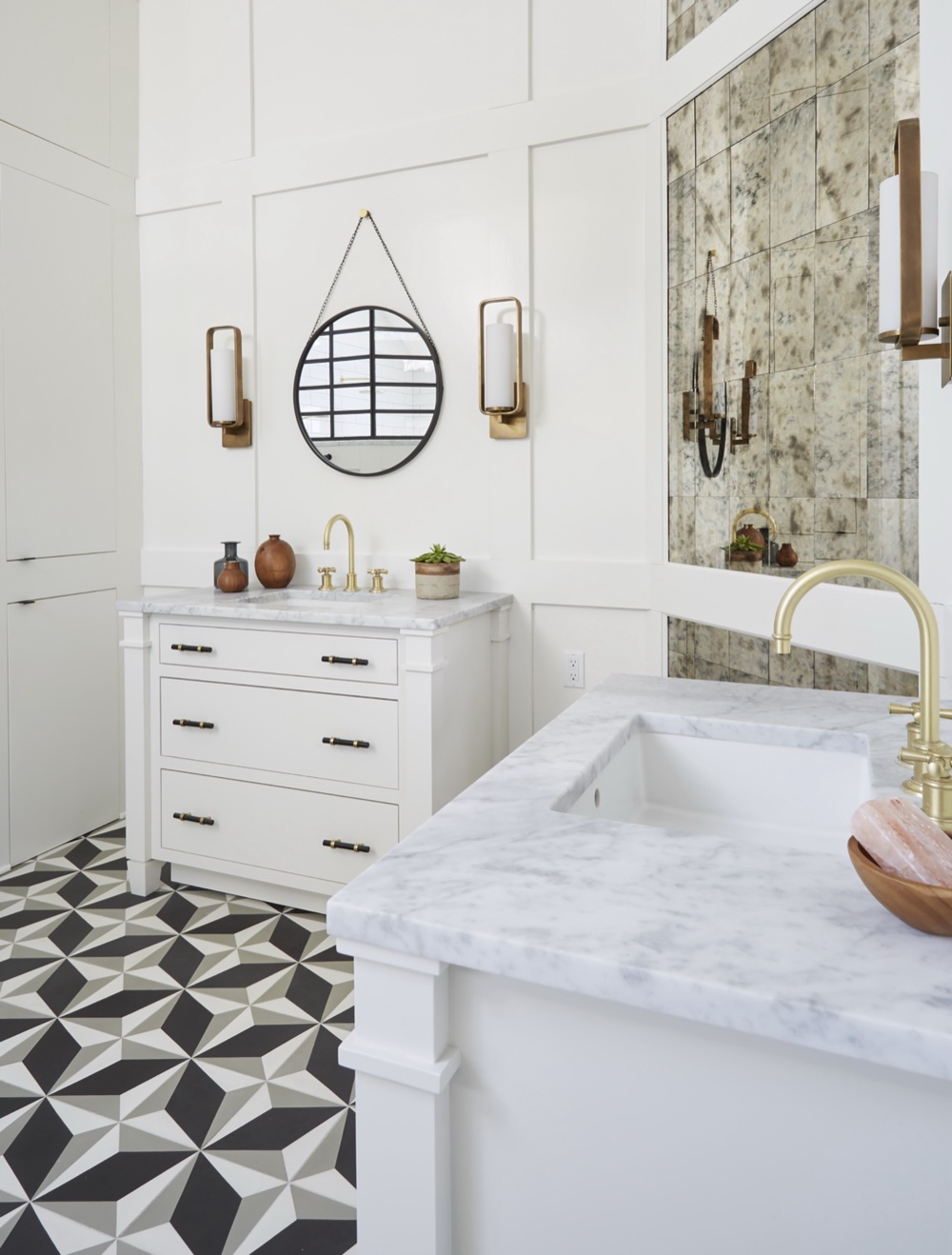 Primary ensuite vanity wall with Carrara marble tops, brass gooseneck faucets, chain-hung round mirror and floor-to-ceiling antique mirror inlay by Martire Custom Homes