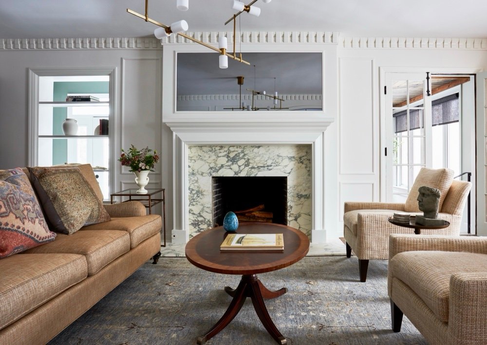 Formal living room with marble fireplace, tailored sofa and modern brass chandelier, by Martire Custom Homes