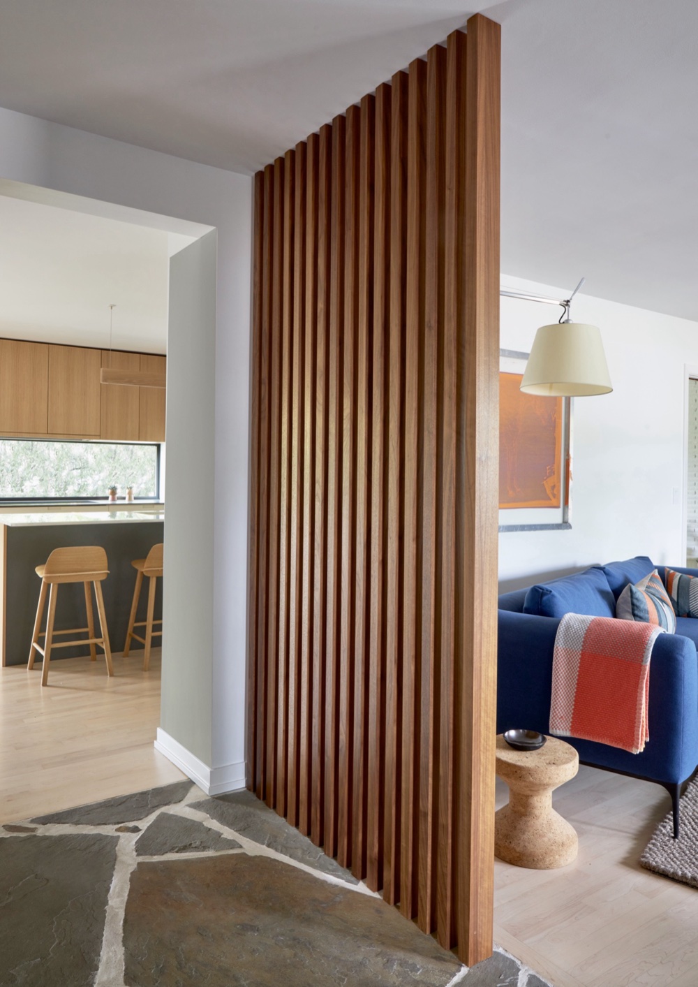 Floor-to-ceiling walnut slat partition wall between the kitchen and living room