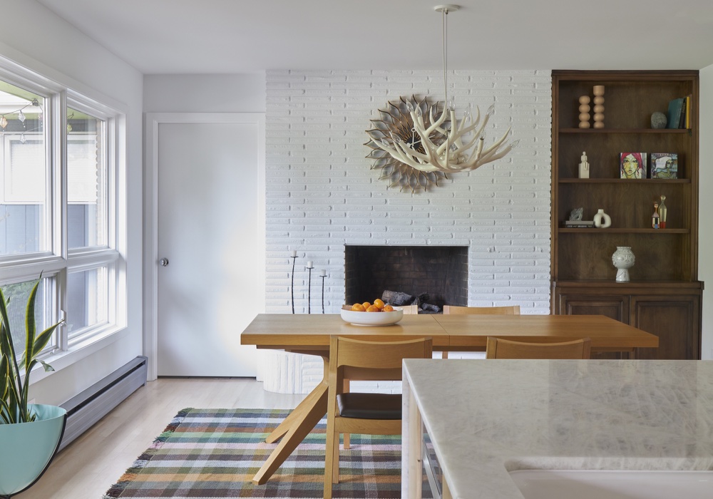 Dining room with oak table, painted white brick fireplace, antler chandelier and walnut hutch