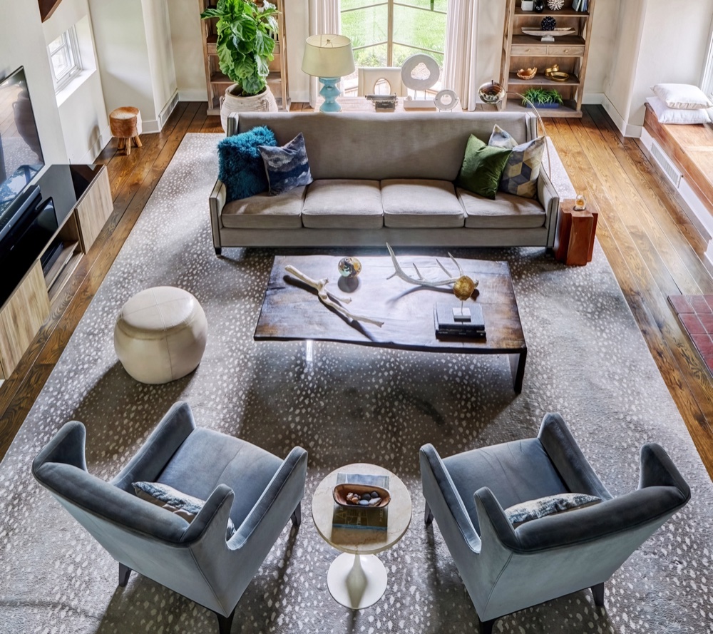 Overhead view of a renovated great room with wide-plank oak flooring, restored beam ends and a window seat, by Martire Custom Homes