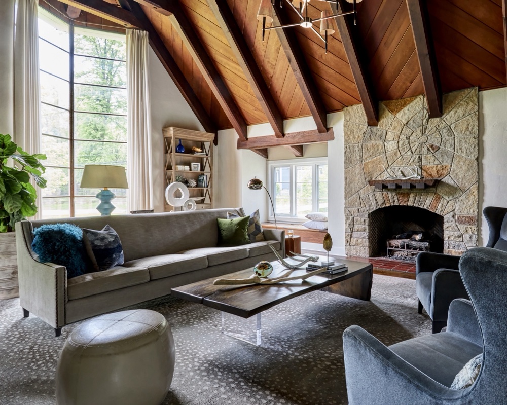 Restored 1920s living room with original stone fireplace laid in a spider-web motif, herringbone firebox and wood plank ceiling with exposed beams, by Martire Custom Homes