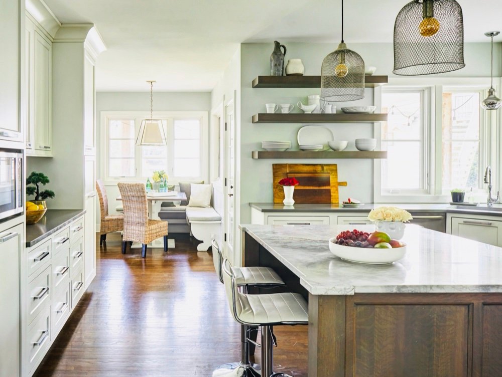 Wide view of the rebuilt storybook kitchen with marble island, open walnut shelving and woven pendants, by Martire Custom Homes