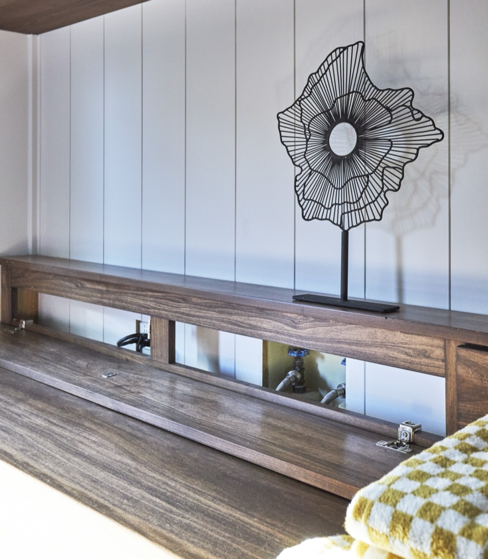 Walnut folding counter with its hinged shelf open, revealing concealed washer and dryer hookups behind custom millwork, by Martire Custom Homes