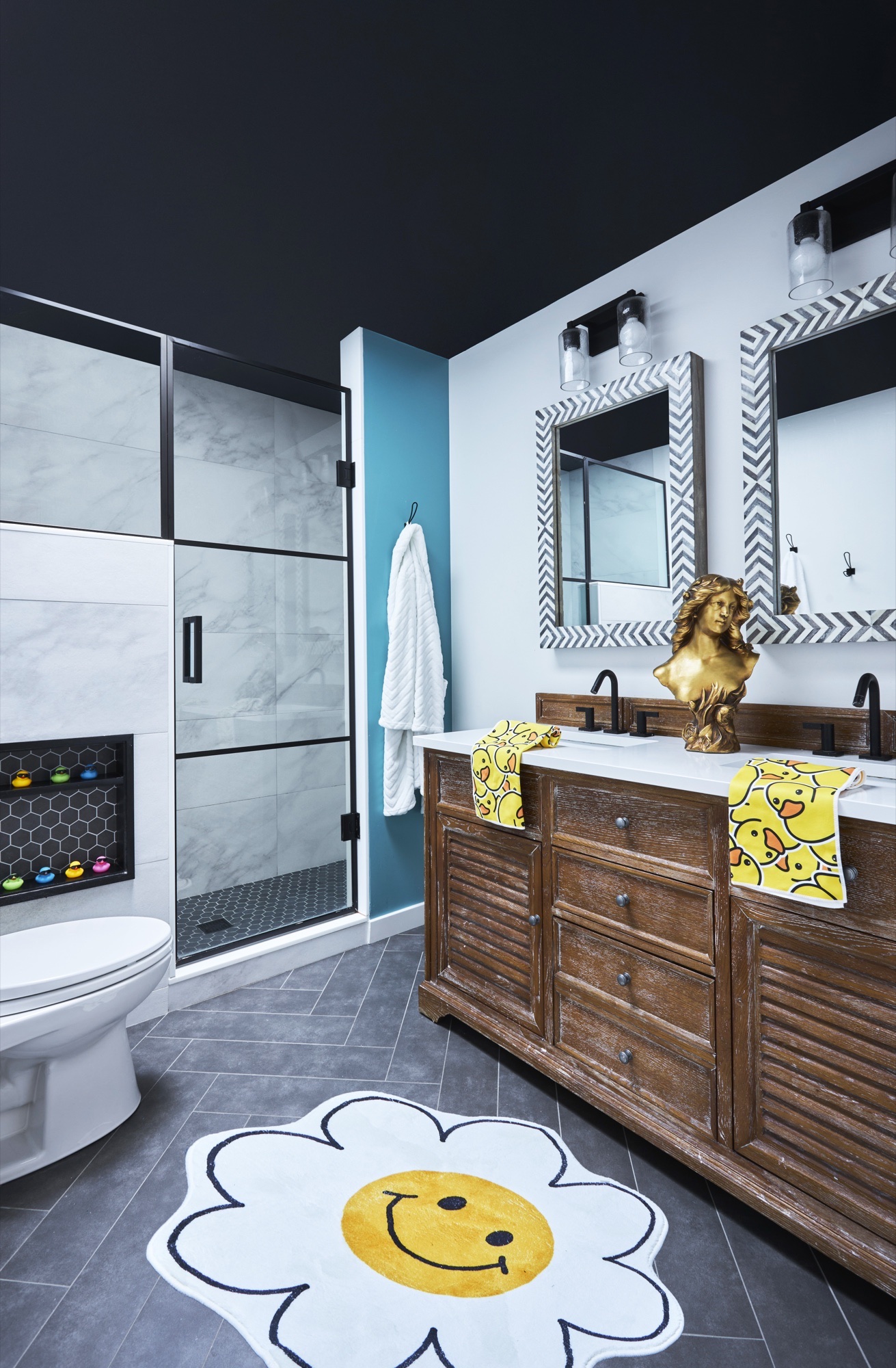 Children's bathroom with black painted ceiling, teal accent wall, marble-look shower surround, honeycomb tile niche and playful daisy rug, by Martire Custom Homes