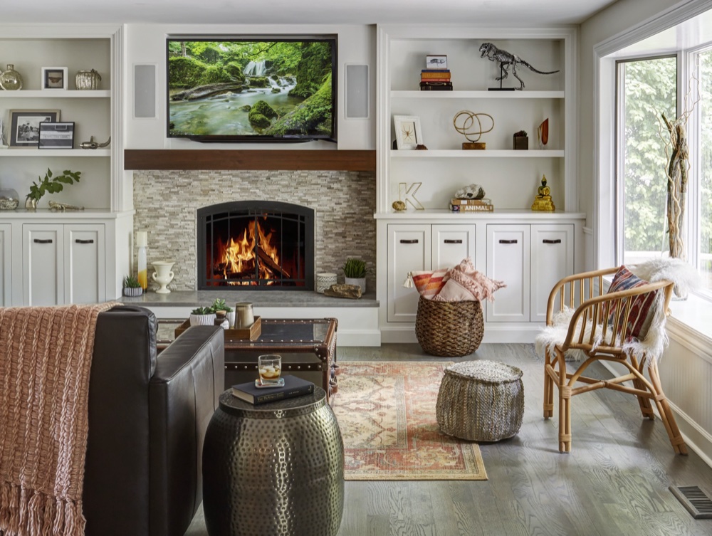 Family room with a stacked-stone tile fireplace, chunky walnut box mantel and painted built-in shelving beside a bright corner window, by Martire Custom Homes