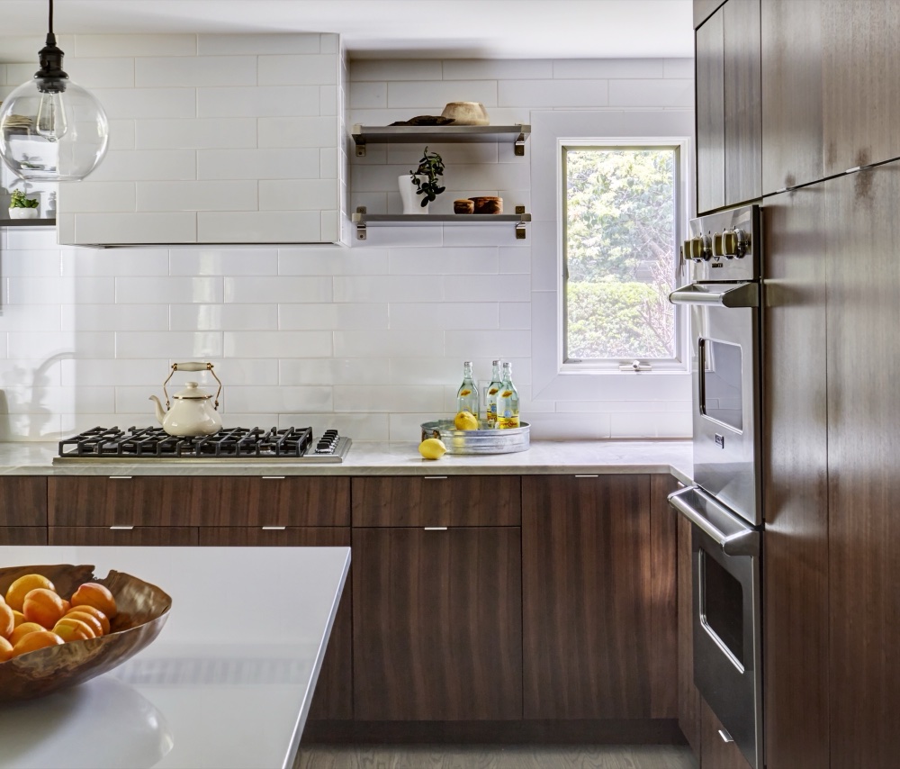 Range wall with a white subway-tiled hood, stainless open shelving, professional gas cooktop and natural quartzite perimeter counters, by Martire Custom Homes